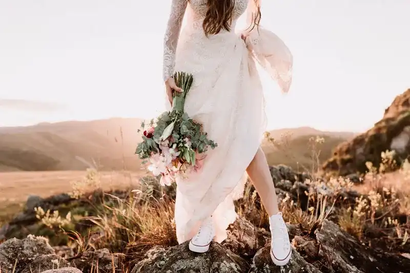 Noiva segurando 
bouquet e saia, com tênis branco