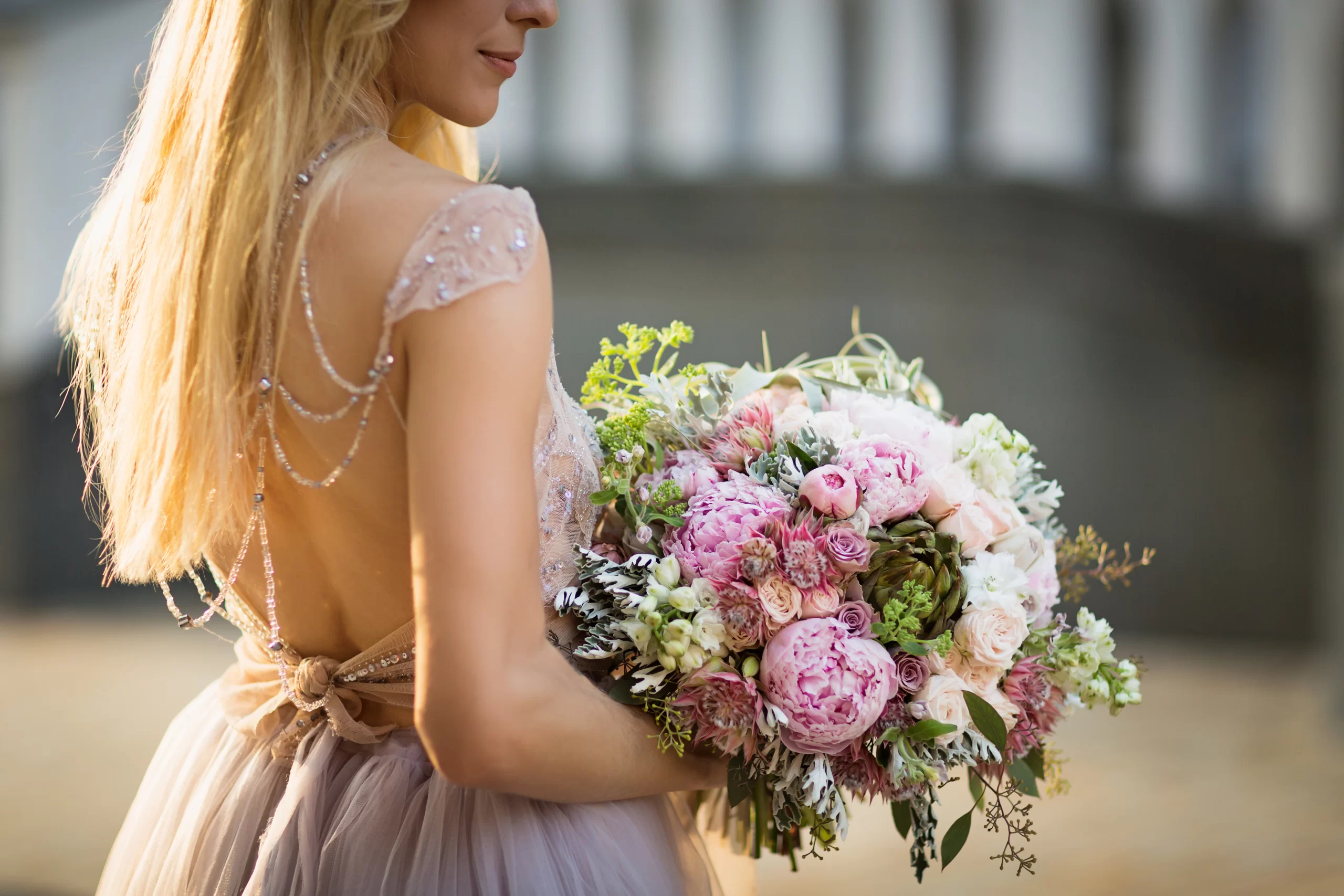 Mulher vestindo um vestido de noiva, com manga curta. Ela seguraum buque de flores.