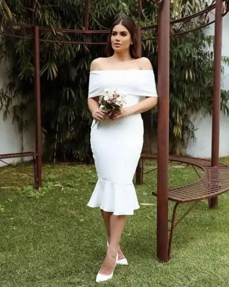 Mulher usando um vestido de noiva branco clássico. Ela segura um buque de flores com as mãos.