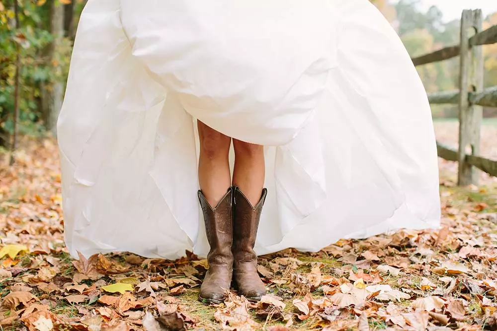 Mulher usando um vestido de noiva branco e calçando uma bota texana.